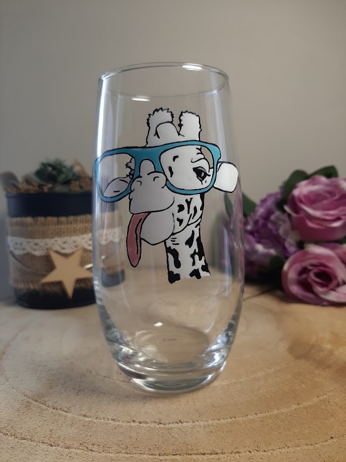 Verre haut transparent avec une girafe rigolote peinte à la main portant de grandes lunettes bleues et tirant la langue, artisanat Aleco.