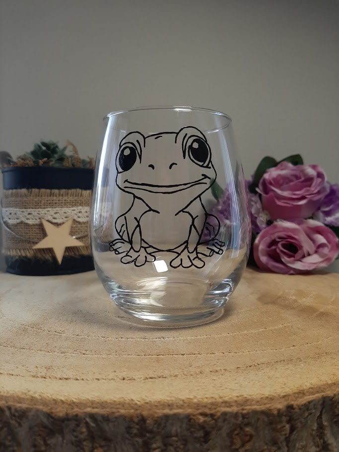 Verre gobelet transparent arrondi avec l'illustration d'une petite grenouille souriante peinte à la main en noir, style graphique épuré, artisanat Aleco Vendée.