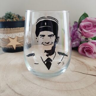 Verre à eau transparent de forme arrondie, décoré d'un portrait stylisé de Louis de Funès dans son rôle du Gendarme de Saint-Tropez, peint à la main en noir, artisanat Aleco.