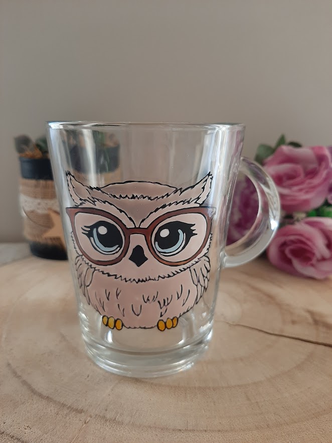 Mug en verre transparent avec anse, décoré d'une illustration artisanale d'une chouette beige aux grands yeux bleus portant des lunettes marron, peinte à la main, artisanat Aleco.