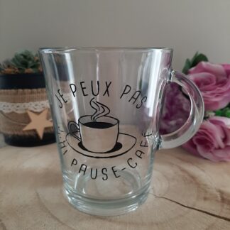 Mug en verre transparent avec anse, décoré d'une illustration d'une tasse de café fumante et de l'inscription humoristique "JE PEUX PAS J'AI PAUSE-CAFÉ" peinte à la main en noir, création artisanale Aleco.
