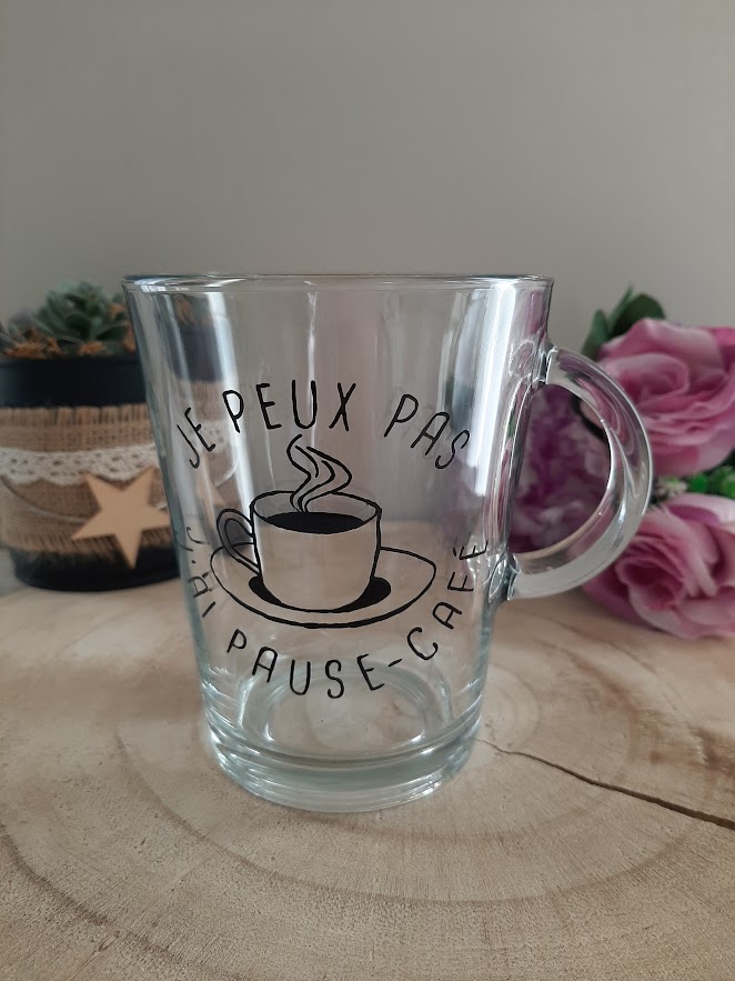 Mug en verre transparent avec anse, décoré d'une illustration d'une tasse de café fumante et de l'inscription humoristique "JE PEUX PAS J'AI PAUSE-CAFÉ" peinte à la main en noir, création artisanale Aleco.