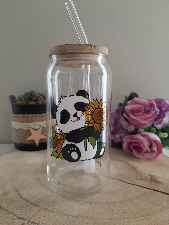 Gobelet en verre transparent avec couvercle en bambou et paille en verre, décoré d'une illustration peinte à la main d'un panda assis tenant un grand tournesol jaune, avec un autre tournesol à ses côtés, artisanat Aleco.