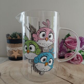 Pichet en verre artisanal Aleco avec trois petits oiseaux ronds (rose, vert, bleu) peints à la main sur une branche.
