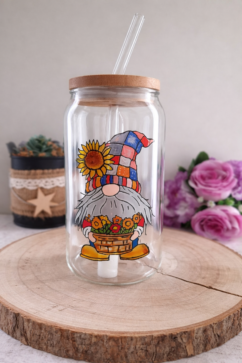 Gobelet paille original en verre transparent avec couvercle en bambou, peint à la main avec une illustration de petit gnome au chapeau patchwork portant un tournesol et un panier de fleurs