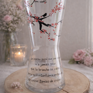 Grand vase transparent en forme de sablier cintré, peint à la main avec un poème calligraphié en noir et une branche de cerisier aux fleurs rouges avec un oiseau, posé sur un support en bois