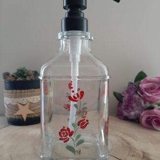 Flacon distributeur de savon en verre avec pompe noire, décoré de roses rouges et de feuilles vertes peintes à la main.
