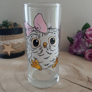 Verre haut transparent avec une petite chouette blanche peinte à la main, portant un nœud rose sur la tête.