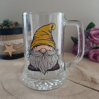 Chope à bière en verre transparent avec une anse, peinte à la main représentant un gnome barbu avec un bonnet jaune.