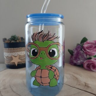 Verre canette transparent avec une tortue verte à lunettes peinte à la main, couvercle bleu et paille en verre.