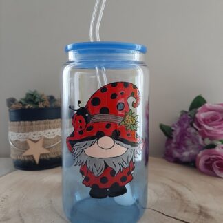 Verre canette transparent avec un gnome déguisé en coccinelle peint à la main, couvercle bleu et paille en verre.