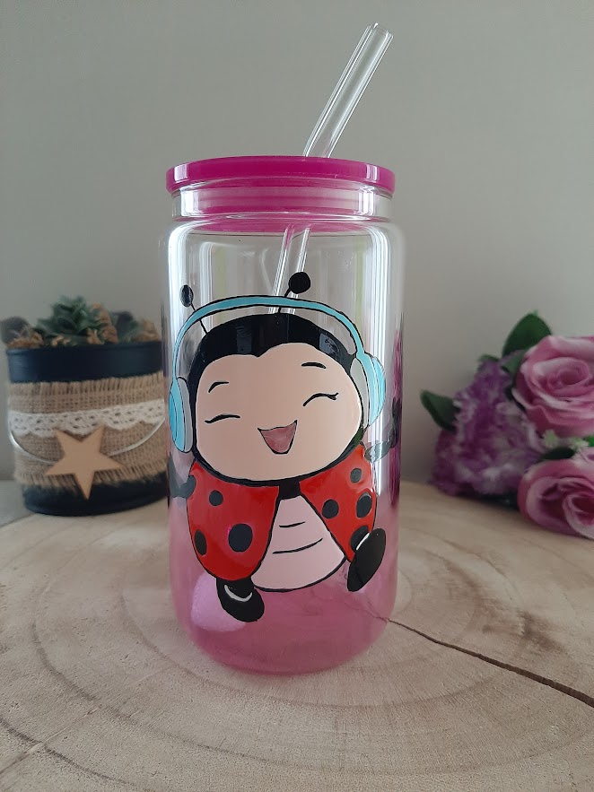 Verre canette rose avec une coccinelle portant un casque audio peinte à la main, couvercle rose et paille en verre.