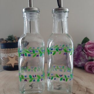 Duo de bouteilles en verre pour huile et vinaigre, décoré de guirlandes de fleurs bleues et violettes peintes à la main.