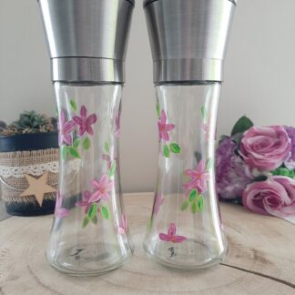Duo de moulins en verre avec têtes en inox, peints à la main avec des fleurs roses et des feuilles vertes.
