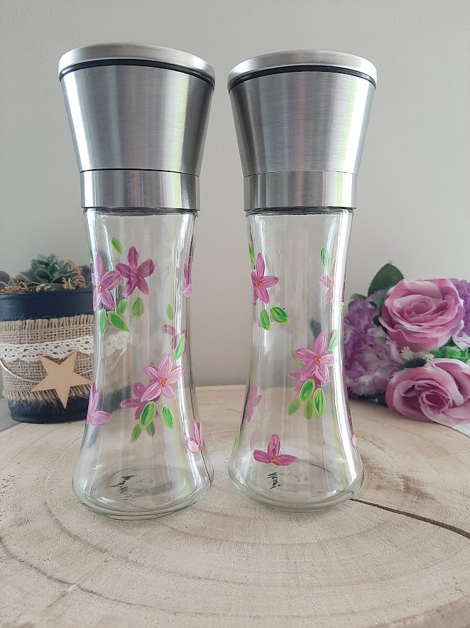 Duo de moulins en verre avec têtes en inox, peints à la main avec des fleurs roses et des feuilles vertes.