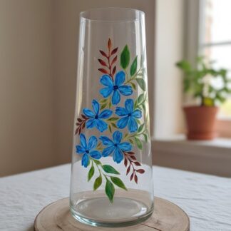 Grand vase en verre de 40 cm de haut, peint à la main avec un motif vertical de fleurs bleues et de feuilles vertes et terracotta, posé sur une tranche de bois
