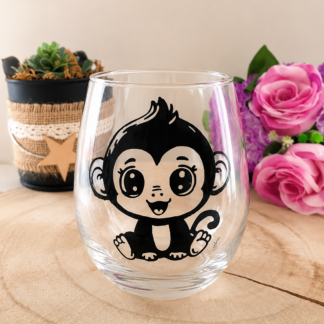 Verre gobelet arrondi de forme bulle, peint à la main avec un motif mignon de petit singe assis en lignes noires, posé sur une tranche de bois