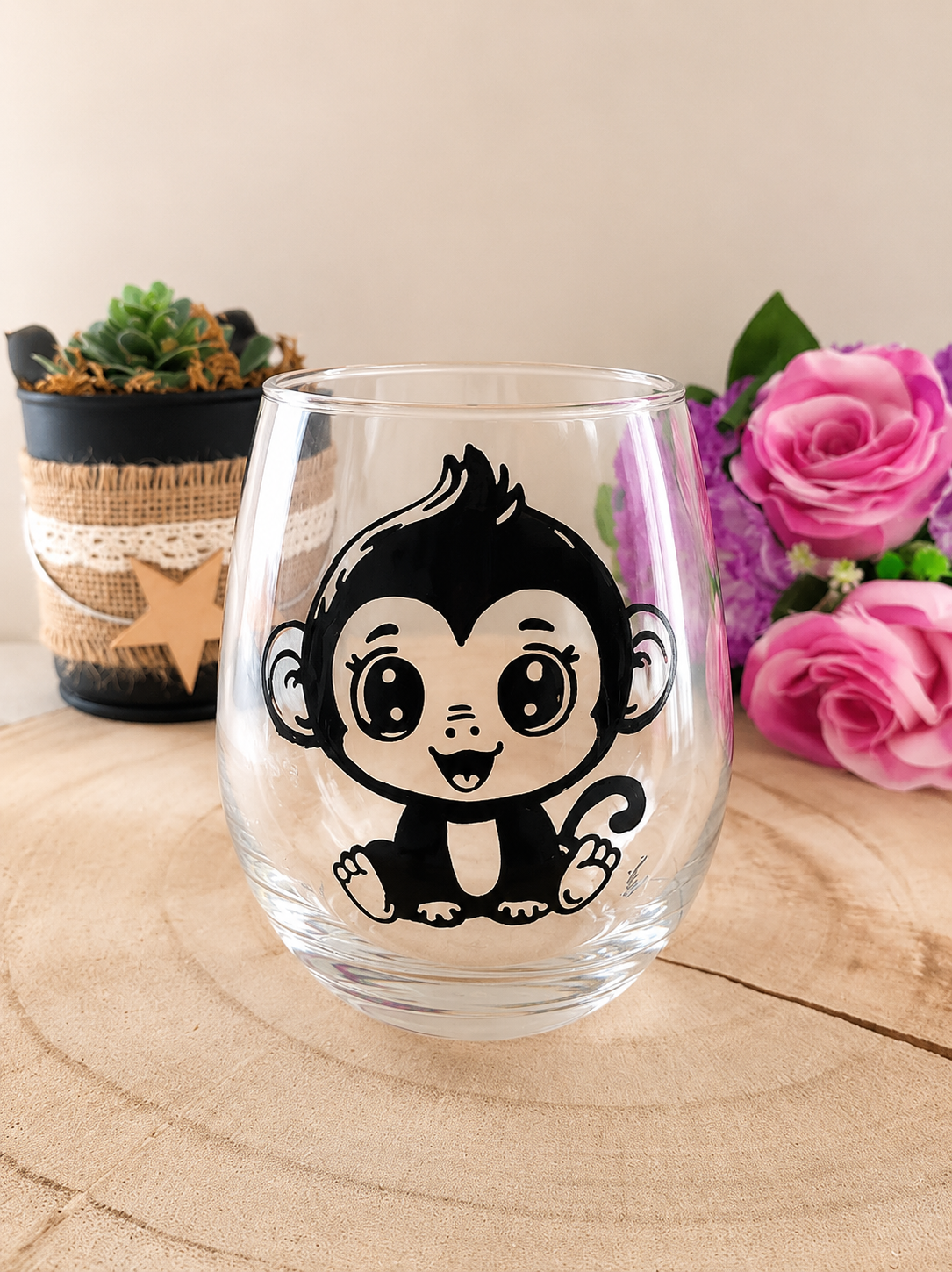 Verre gobelet arrondi de forme bulle, peint à la main avec un motif mignon de petit singe assis en lignes noires, posé sur une tranche de bois