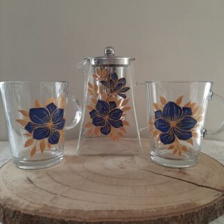 Service à thé en verre composé d'une théière et deux mugs avec décor de fleurs bleues et feuilles dorées fait main.