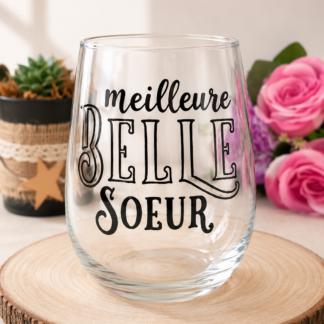 Verre à message peint à la main « Meilleure Belle Sœur » avec typographie décorative élégante, posé sur une rondelle de bois avec des roses roses en arrière plan