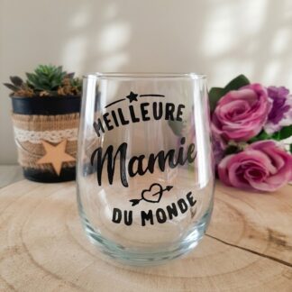 Verre à message peint à la main « Meilleure Mamie du Monde » avec étoile et cœur décoratifs, posé sur une rondelle de bois avec des roses roses en arrière plan