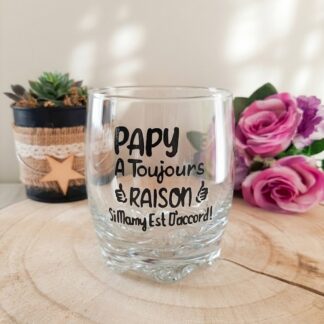 Verre taillé à message humoristique peint à la main « Papy a Toujours Raison Si Mamy Est D'accord » posé sur une rondelle de bois avec des roses roses en arrière plan