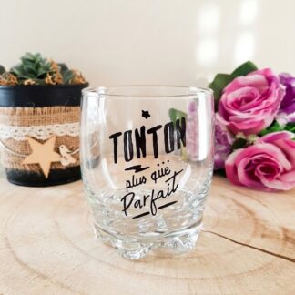 Verre taillé à message peint à la main « Tonton Plus que Parfait » avec étoile décorative, posé sur une rondelle de bois avec des roses en arrière plan