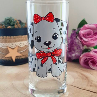 Verre droit peint à la main avec chiot dalmatien et nœuds rouges à pois, posé sur une table en bois avec des roses roses