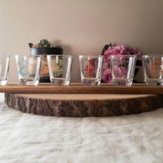 Coffret de 6 verres à shot peints à la main avec chiffres de 1 à 6 en pointillés colorés, présentés sur leur planchette en bois sur une table en bois