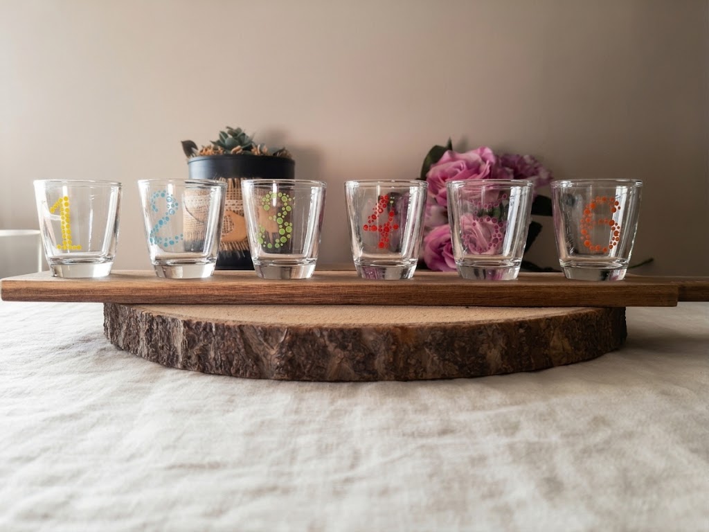 Coffret de 6 verres à shot peints à la main avec chiffres de 1 à 6 en pointillés colorés, présentés sur leur planchette en bois sur une table en bois