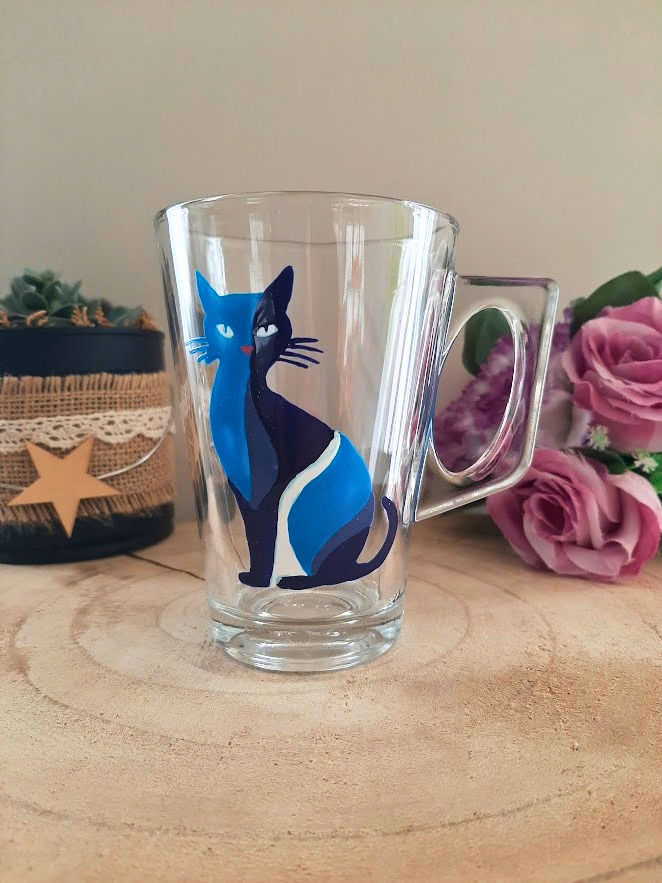 Mug en verre peint à la main avec chat bleu élégant, posé sur une table en bois