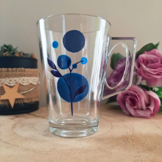Mug en verre peint à la main avec fleur bleue abstraite composée de ronds, posé sur une table en bois