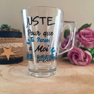 Mug en verre peint à la main avec message romantique "Juste pour que tu penses à moi le matin", posé sur une table en bois
