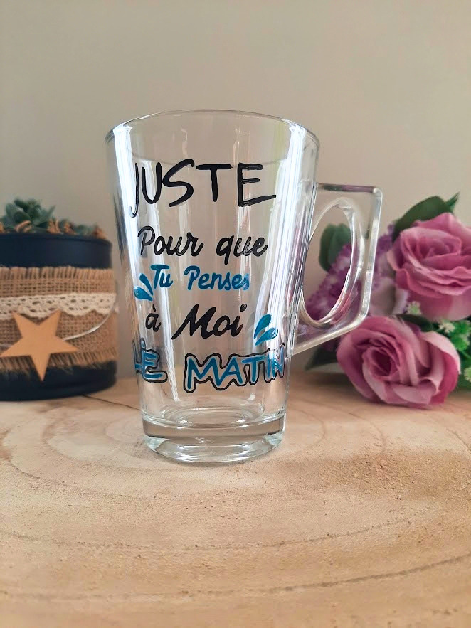 Mug en verre peint à la main avec message romantique "Juste pour que tu penses à moi le matin", posé sur une table en bois