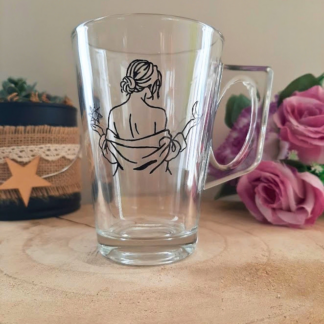 Mug en verre peint à la main avec silhouette de femme de dos, style line art, posé sur une table en bois