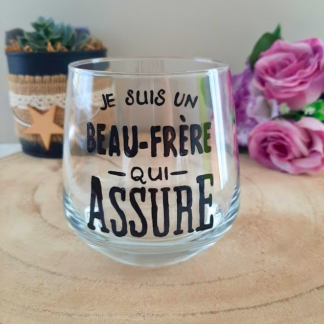 Verre à message peint à la main "Je suis un beau-frère qui assure", posé sur une table en bois avec des fleurs roses