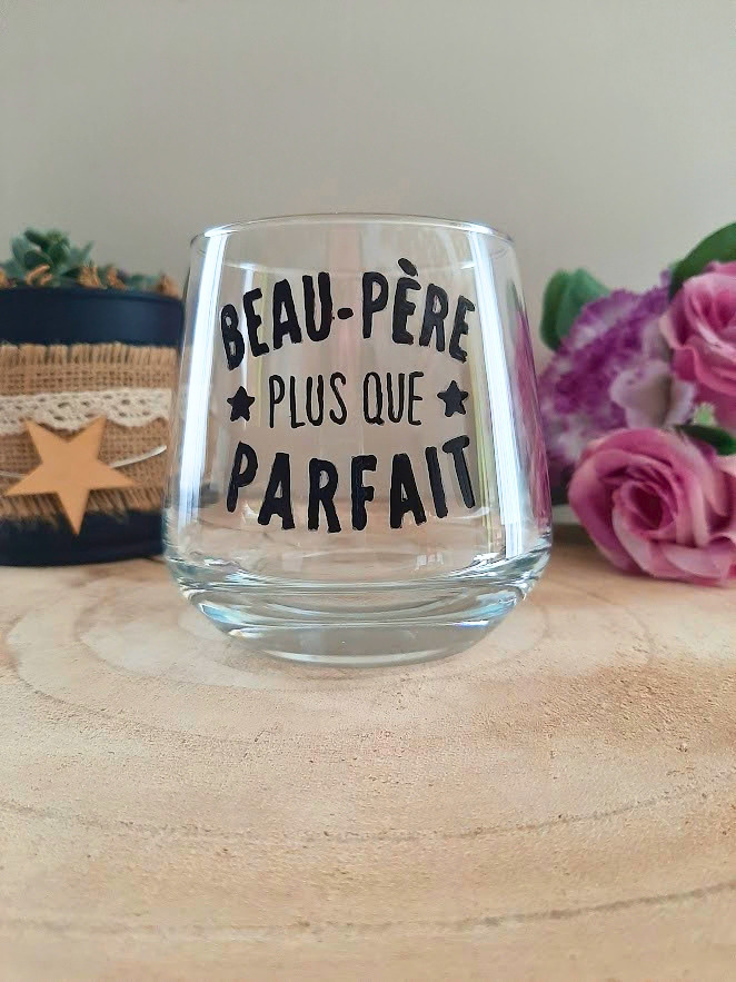 Verre à message peint à la main "Beau-père plus que parfait" avec petites étoiles, posé sur une table en bois avec des fleurs roses