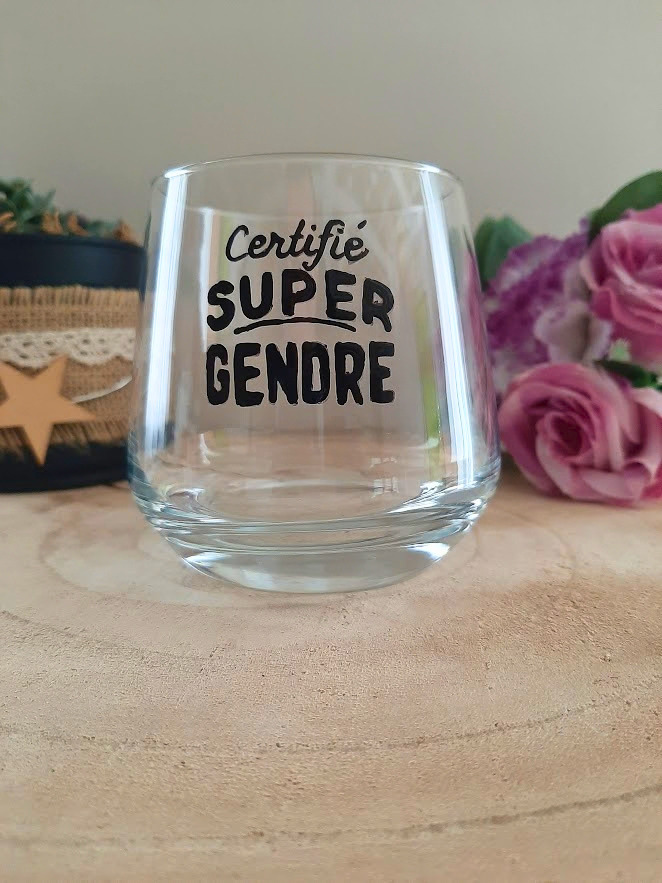 Verre à message peint à la main "Certifié super gendre", posé sur une table en bois avec des fleurs roses