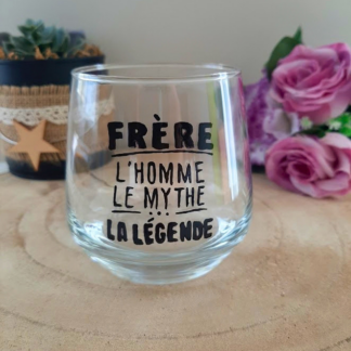 Verre à message peint à la main "Frère, l'homme, le mythe, la légende", posé sur une table en bois avec des fleurs roses