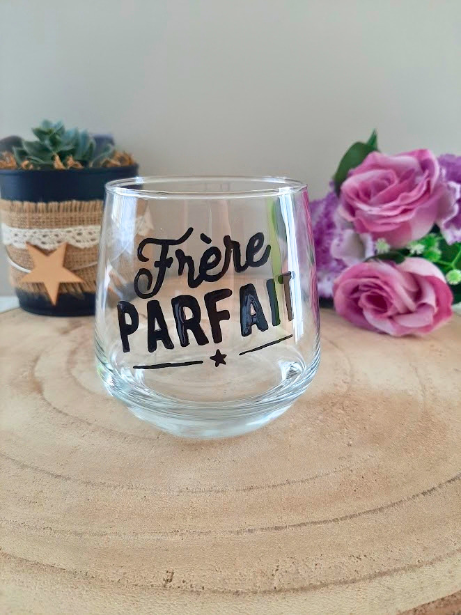 Verre à message peint à la main "Frère parfait" avec petite étoile, posé sur une table en bois avec des fleurs roses
