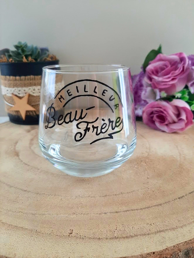 Verre à message peint à la main "Meilleur beau-frère" en calligraphie arquée, posé sur une table en bois avec des fleurs roses