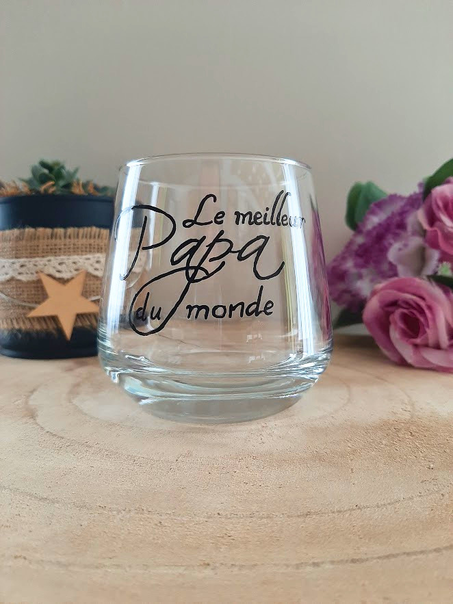 Verre à message peint à la main "Le meilleur Papa du monde", calligraphie noire, posé sur une table en bois avec des fleurs roses