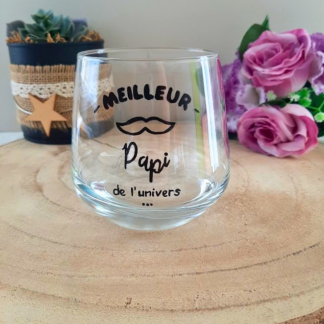 Verre à message peint à la main "Meilleur Papi de l'univers" avec petite moustache illustrée, posé sur une table en bois avec des fleurs roses