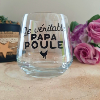 Verre à message peint à la main "Le véritable papa poule" avec petite poule illustrée, posé sur une table en bois avec des fleurs roses