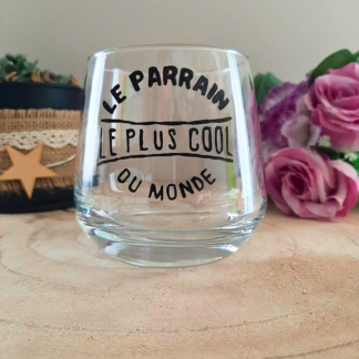 Verre à message peint à la main "Le parrain le plus cool du monde", posé sur une table en bois avec des fleurs roses