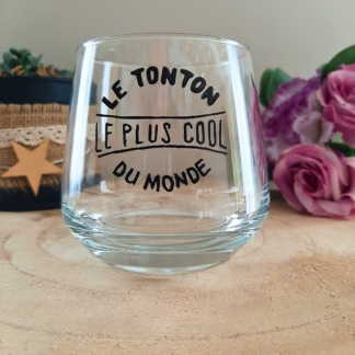 Verre à message peint à la main "Le tonton le plus cool du monde", posé sur une table en bois avec des fleurs roses