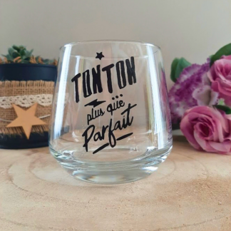 Verre à message peint à la main "Tonton plus que parfait" avec petite étoile, posé sur une table en bois avec des fleurs roses